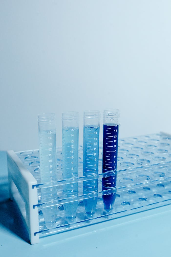 Array of test tubes filled with liquid in a laboratory setup on a monochrome background.