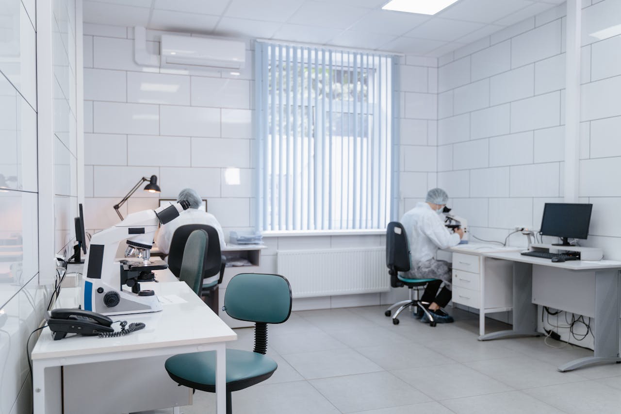 Clean, modern laboratory interior with microscopes and researchers in protective gear conducting analysis.